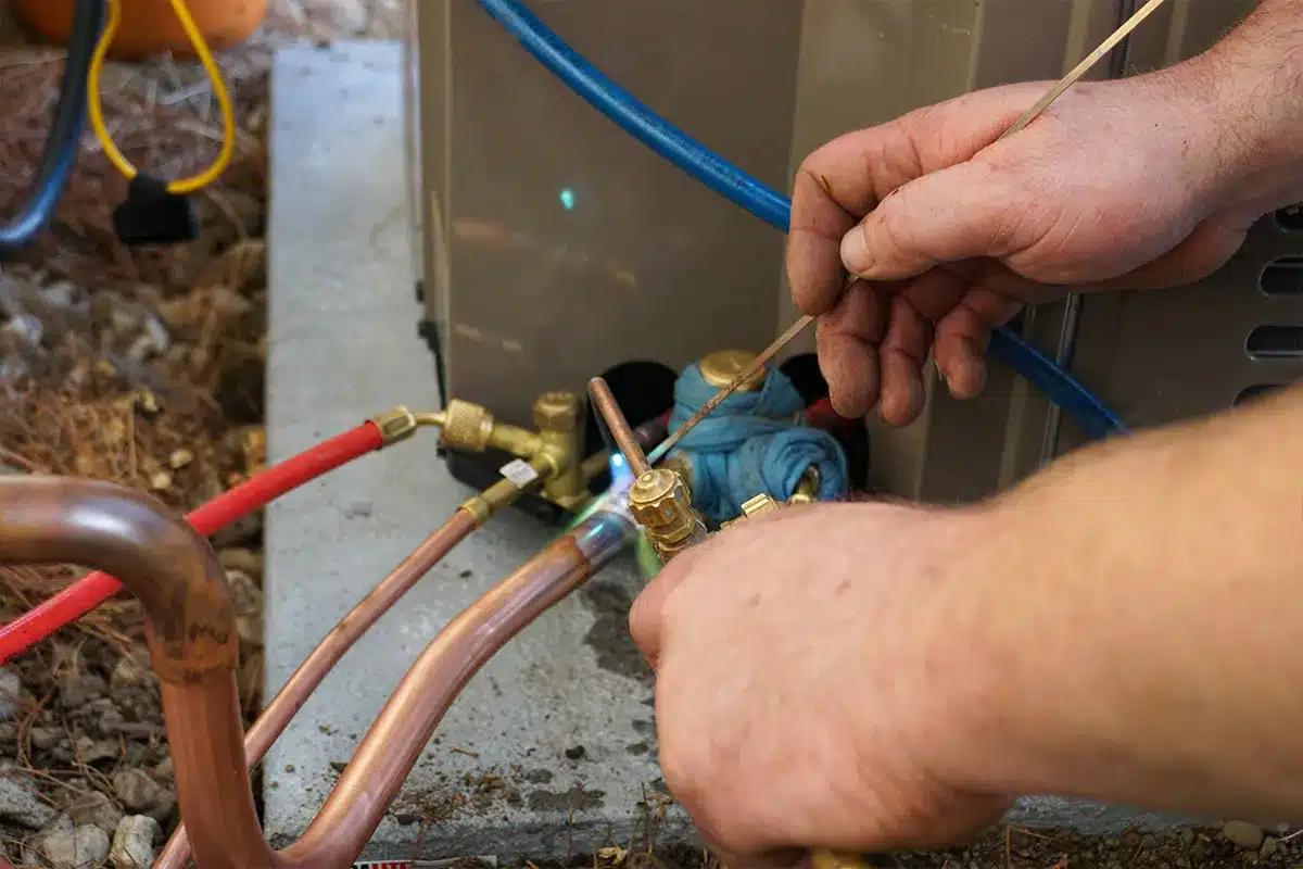 An HVAC technician brazes a refrigeration line set